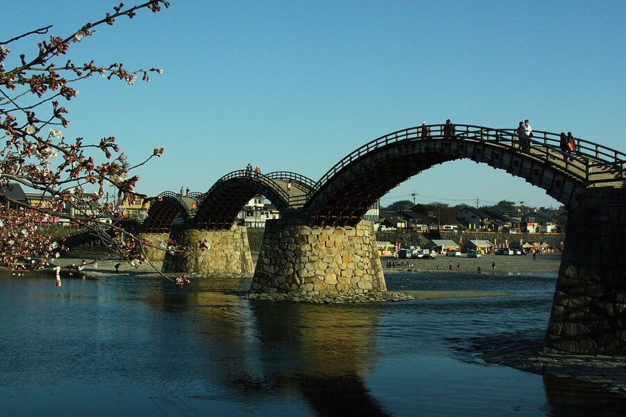 The Kintaikyo Bridge during cherry blossom season with trees in full bloom along the riverbank