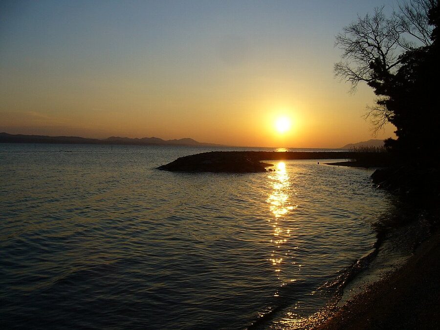 A small fishing boat on Lake Shinji at dawn with the lake shimmering