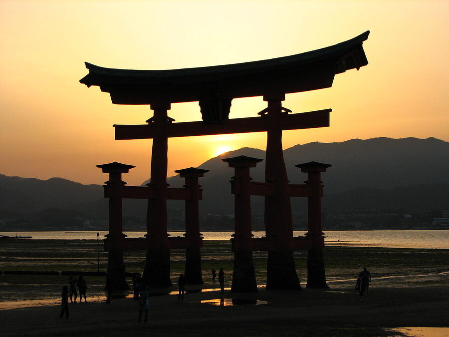 The floating torii of Itsukushima Shrine at sunset with the gate silhouetted in the water