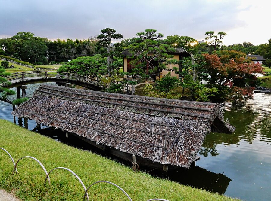 Garden bridge crossing a stream at Okayama Korakuen with manicured hedges