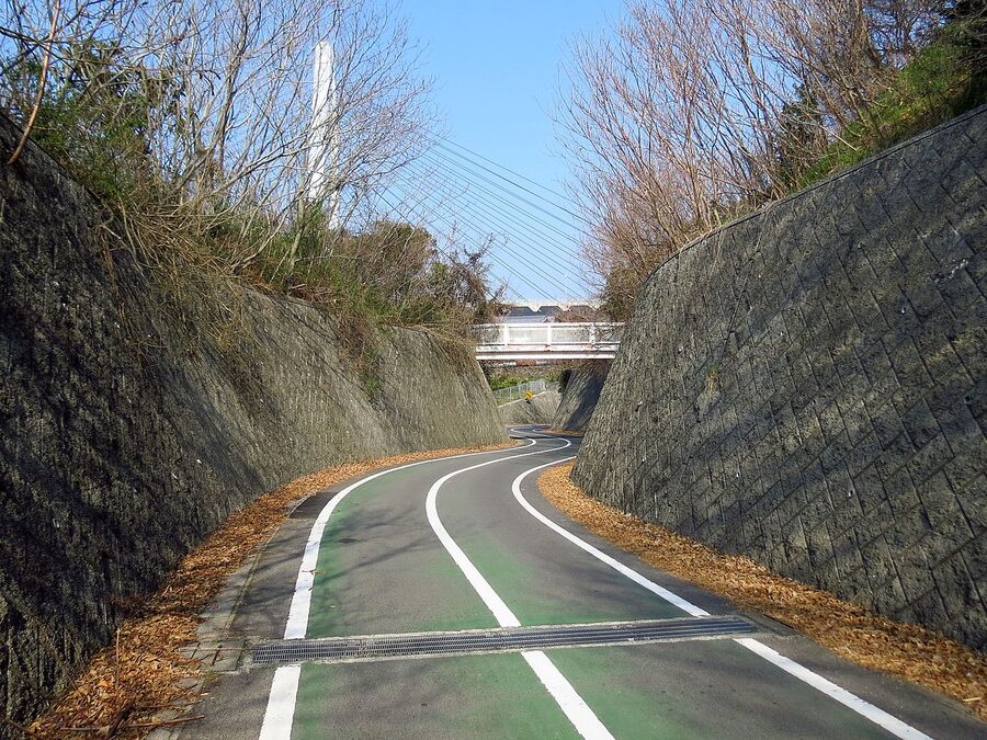 A cyclist on the dedicated cycling path of the Shimanami Kaido with a suspension bridge ahead