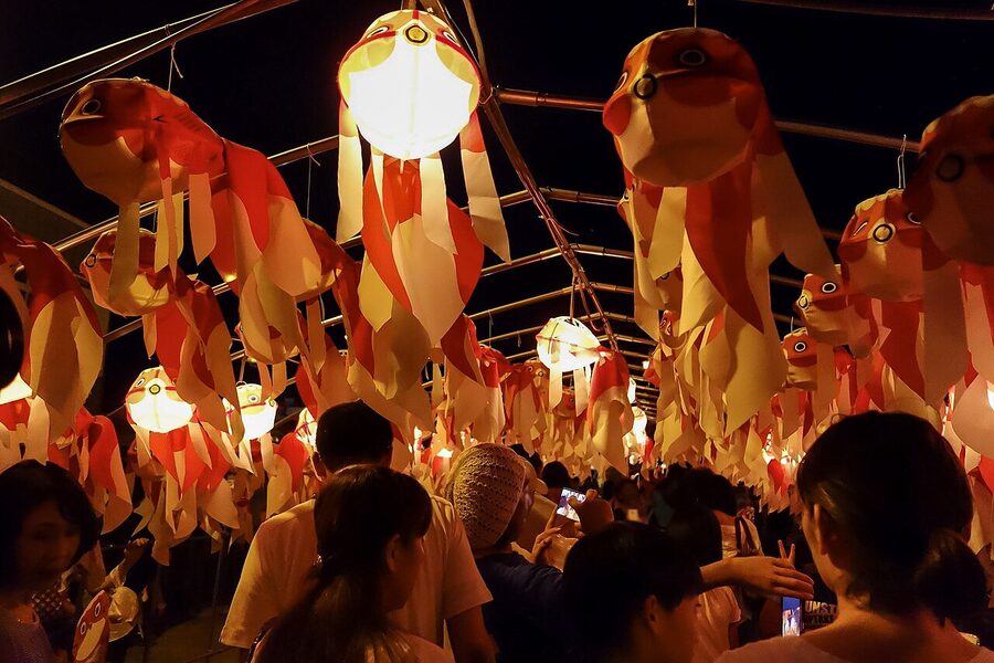 A tunnel of hundreds of goldfish lanterns illuminated at night in Yanai