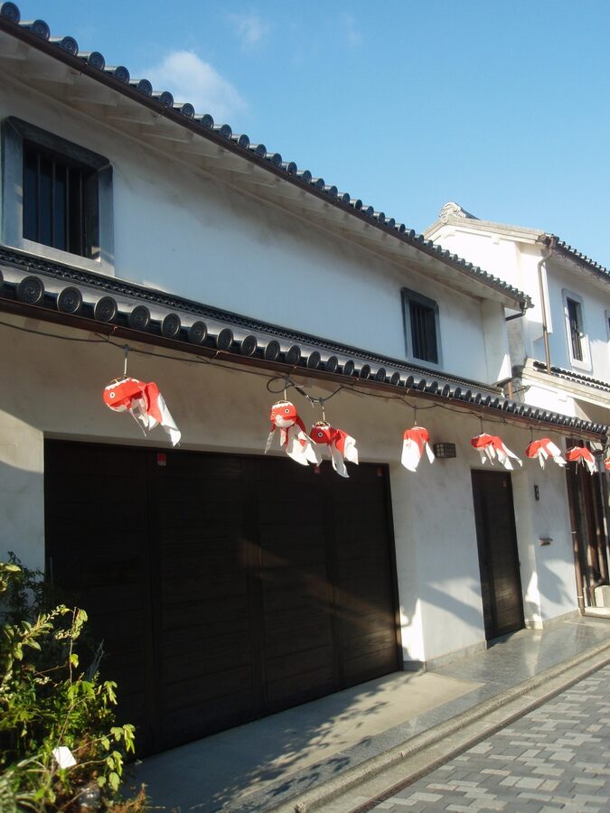 Small goldfish lanterns hanging along a whitewashed wall in Yanai